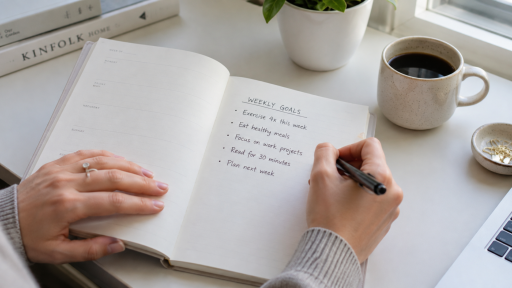 Person writing weekly goals as part of a plan to focus on yourself